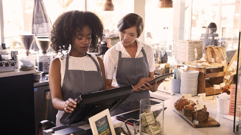 New starter being taught how to use checkout till