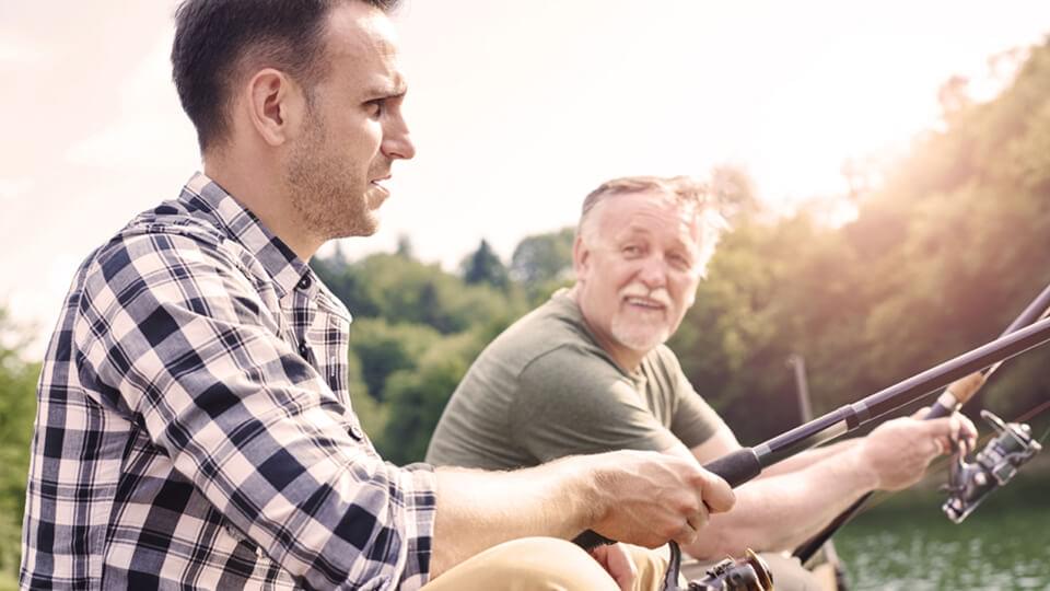 Senior man with son fishing by the lake